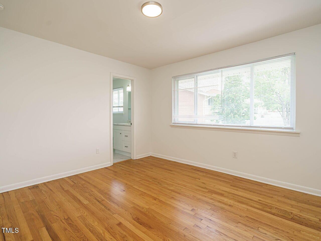 2316 Champion Court Raleigh, NC 27606 - Photo 19 of 27 a view of an empty room with wooden floor and a window