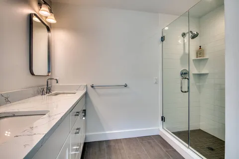 a bathroom with a granite countertop sink mirror and shower