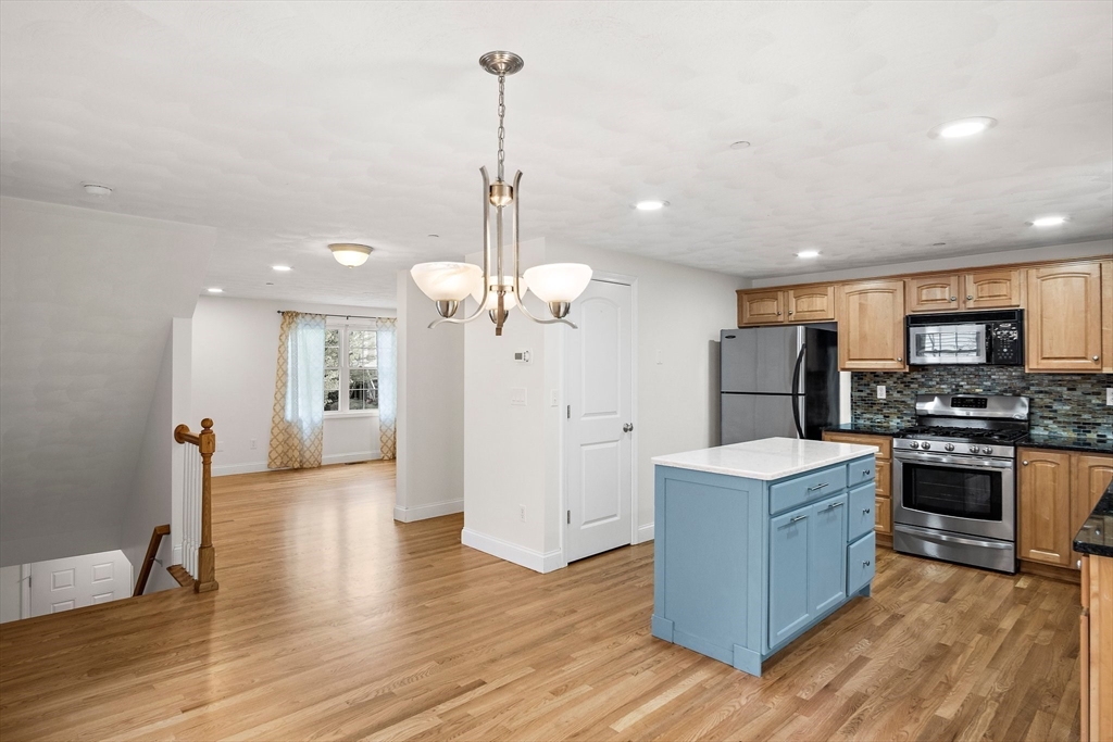 81 Salem Road, Unit 21 Billerica, MA 01821 - Photo 6 of 21 a view of a kitchen with stainless steel appliances granite countertop wooden floors and a view of living room