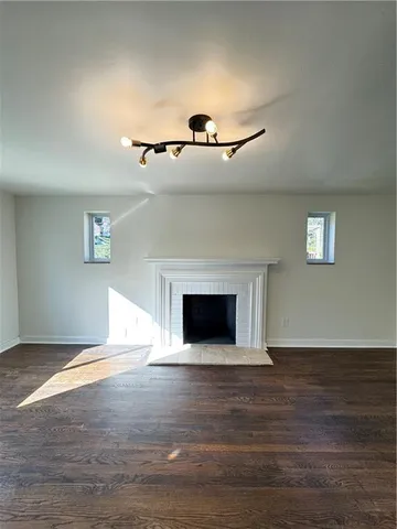a view of an empty room with wooden floor and a fireplace