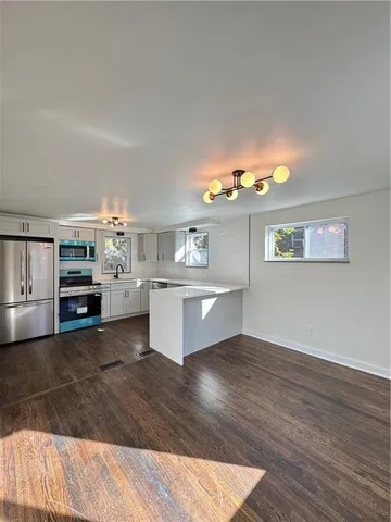 a large white kitchen with a stove a sink dishwasher and a fireplace with wooden floor