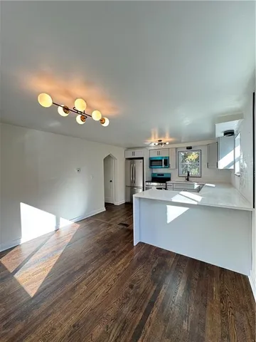 a view of a kitchen with kitchen island a sink wooden floor and a large window