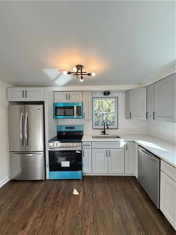 a kitchen with cabinets stainless steel appliances and wooden floor