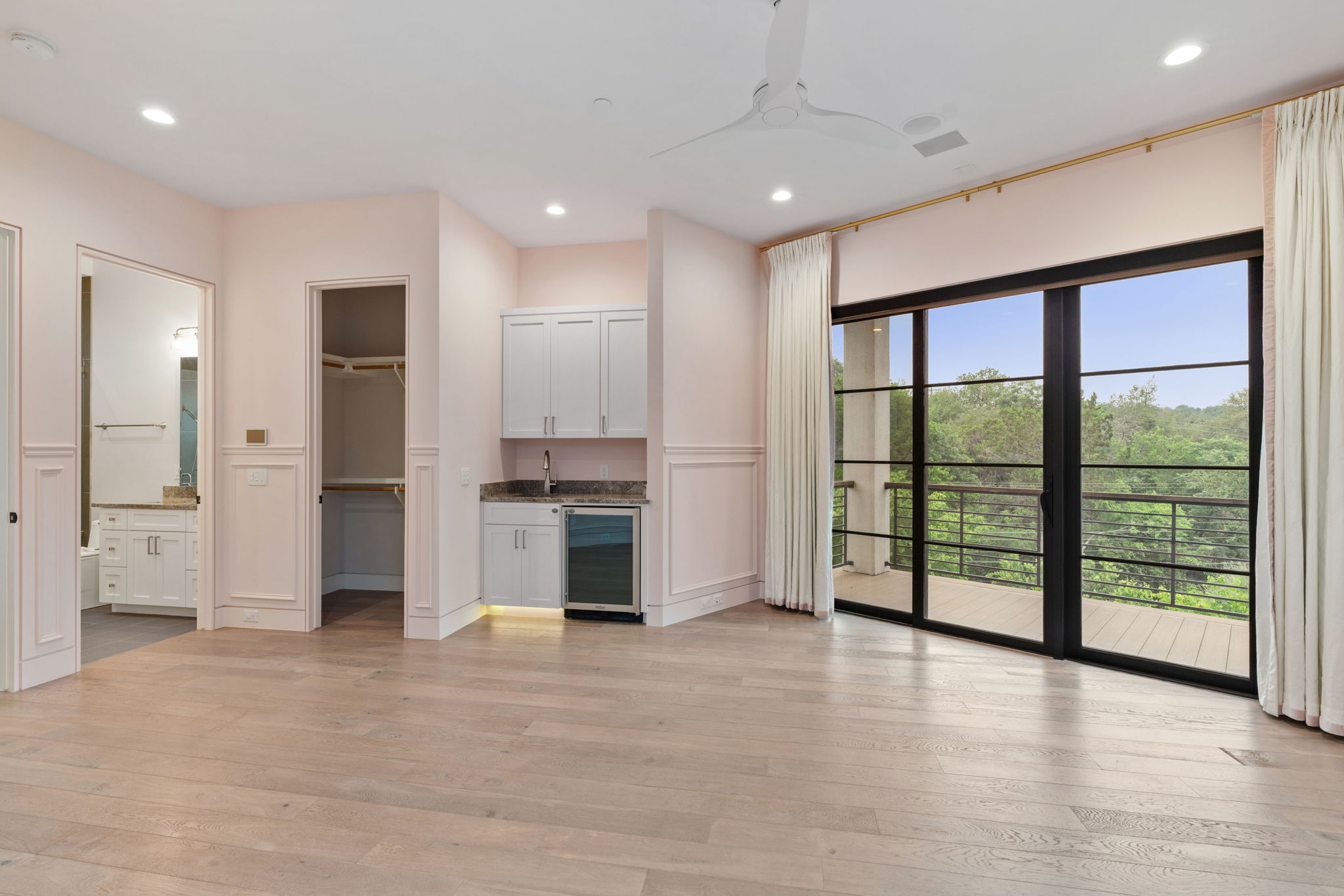 604 Brookhaven Trail Austin, TX 78746 - Photo 16 of 38 Mother-in-law suite on the main level. Hardwood flooring throughout, featuring a wet bar with cabinetry and beverage refrigerator, a walk-in closet, and an attached bathroom.