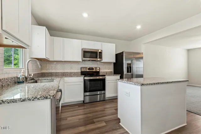 a kitchen with granite countertop a sink stove and refrigerator