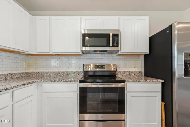 a kitchen with stainless steel appliances granite countertop white cabinets and a stove