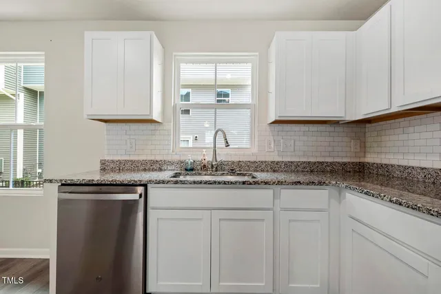 a kitchen with granite countertop white cabinets and a sink
