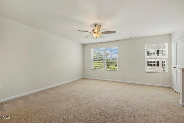 an empty room with windows and ceiling fan