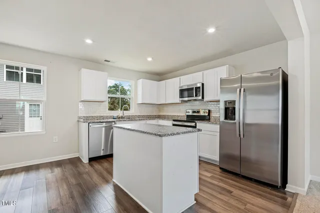 a kitchen with stainless steel appliances granite countertop a refrigerator a stove a sink and a microwave