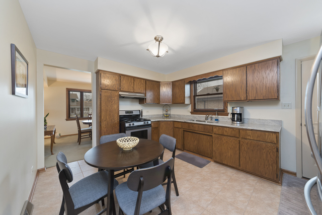 10700 Austin Avenue Chicago Ridge, IL 60415 - Photo 5 of 19 a kitchen with stainless steel appliances granite countertop a sink dishwasher a stove a refrigerator with a dining table and chairs
