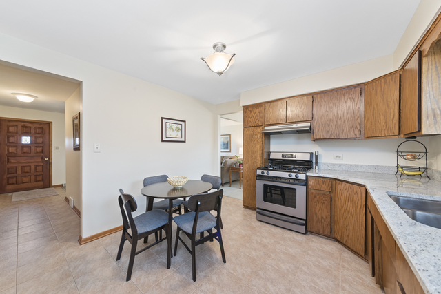 10700 Austin Avenue Chicago Ridge, IL 60415 - Photo 7 of 19 a kitchen with stainless steel appliances granite countertop a stove top oven a sink a dining table and chairs with wooden floor