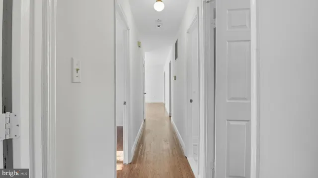 a view of a hallway with wooden floor and a bathroom