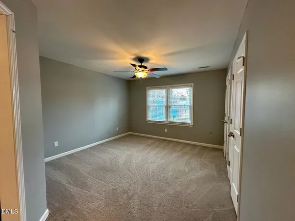 an empty room with closet and a ceiling fan
