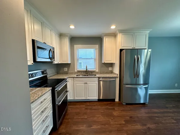 a kitchen with granite countertop a refrigerator oven a sink and dishwasher