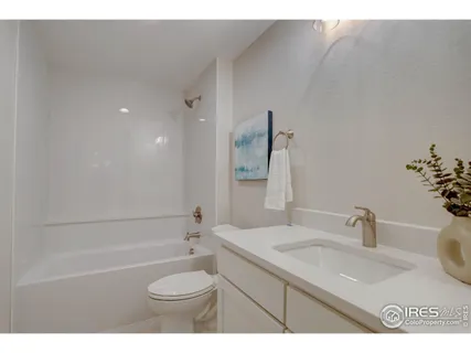 a bathroom with a sink toilet granite vanity and bathtub
