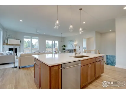 a kitchen with a sink a counter top space and living room view