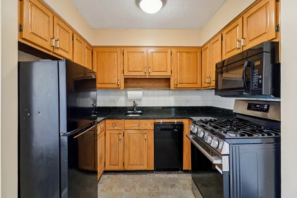 a kitchen with stainless steel appliances granite countertop a stove a sink and a microwave
