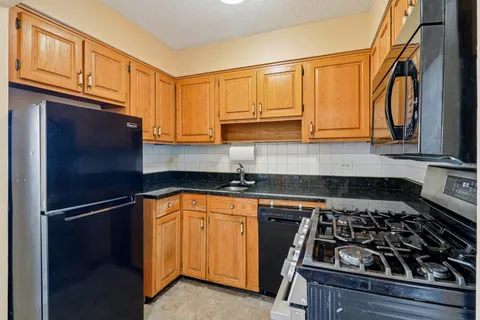 a kitchen with granite countertop stainless steel appliances a sink a stove cabinets and a counter top space