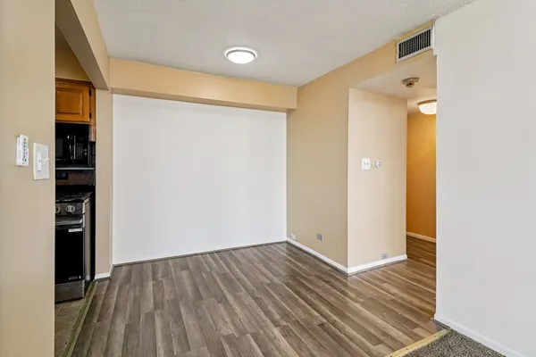 a view of an empty room with closet and wooden floor