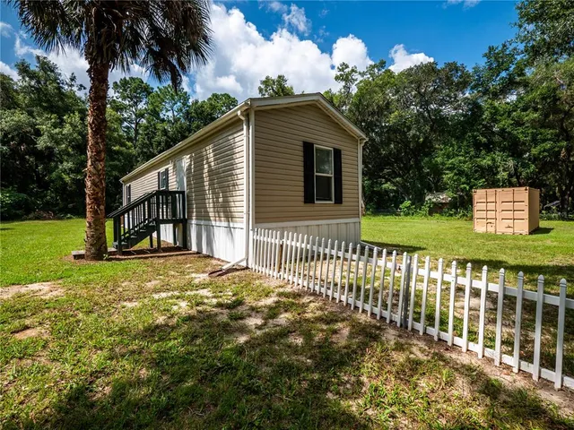 a backyard of a house with large trees and wooden fence