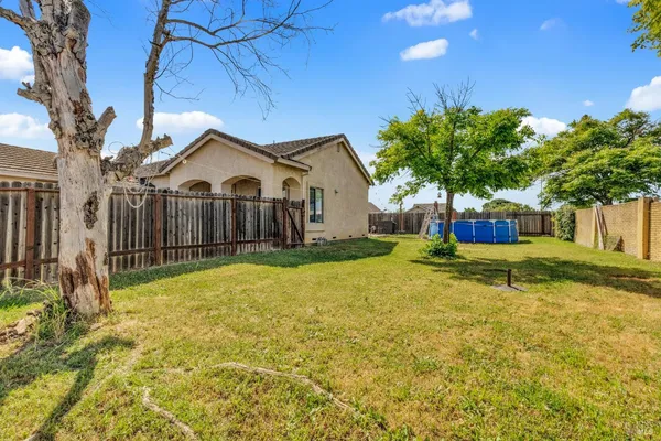 a view of a house with a yard and large tree