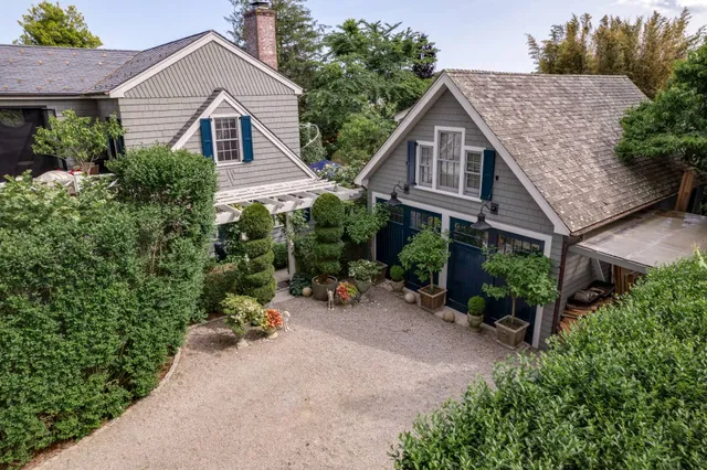 a view of a brick house with potted plants and a bench