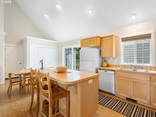 a large white kitchen with a stove a sink a dining table and chairs