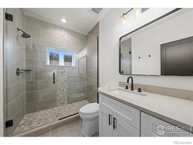 a bathroom with a sink a toilet a mirror and shower