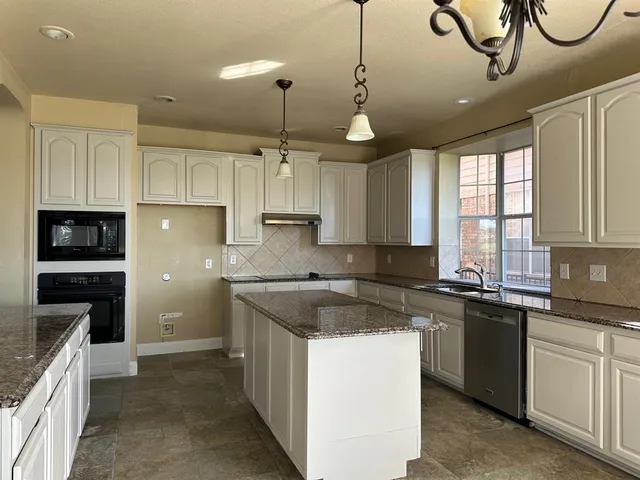 a kitchen with kitchen island granite countertop a sink a counter top space and living room view