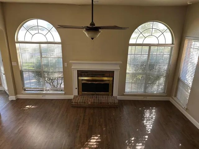an empty room with wooden floor a fireplace and a large window