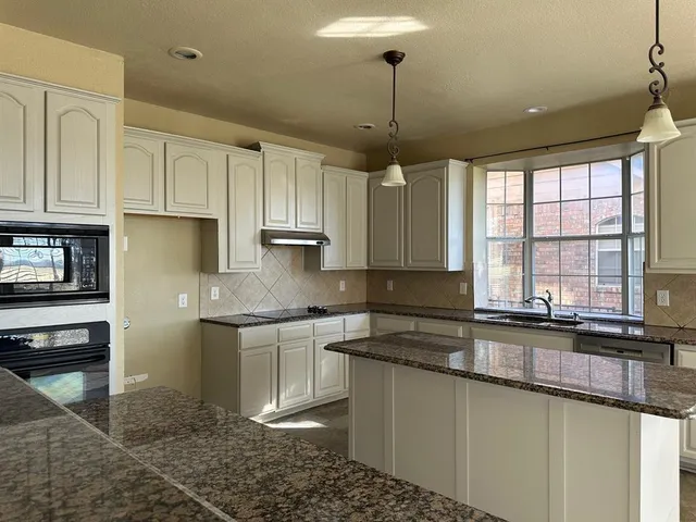 a kitchen with stainless steel appliances granite countertop a stove a sink and a refrigerator