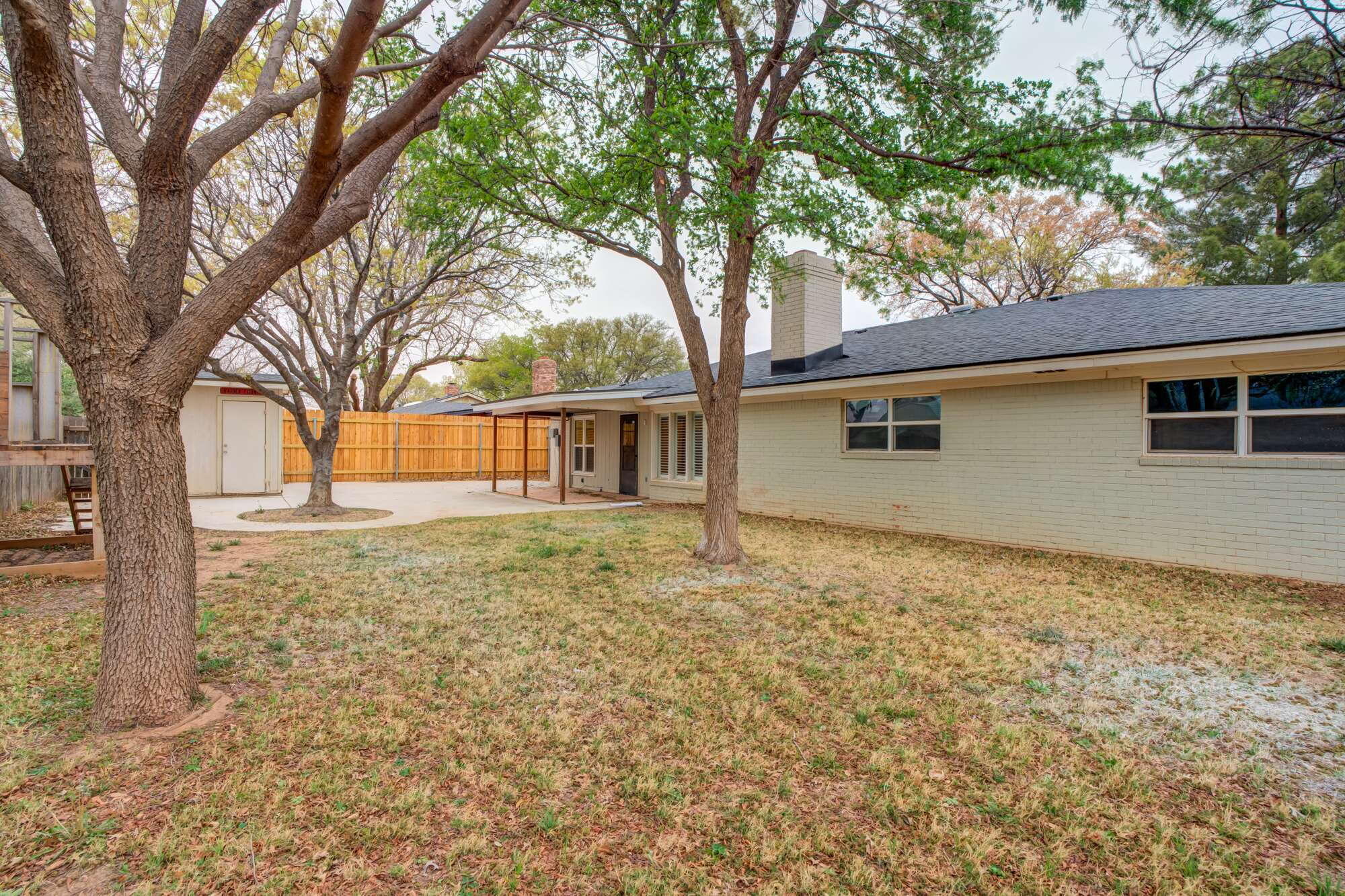 5309 77th Street Lubbock, TX 79424 - Photo 33 of 36 a backyard of a house with large trees and wooden fence