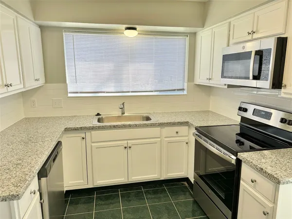 a kitchen with granite countertop cabinets stainless steel appliances and a sink