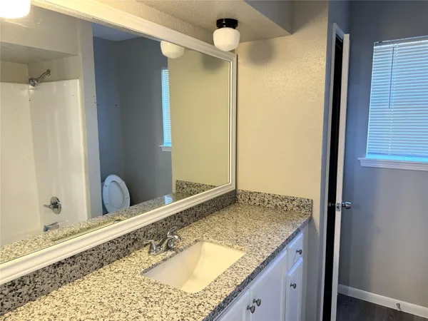 a bathroom with a granite countertop sink and a mirror