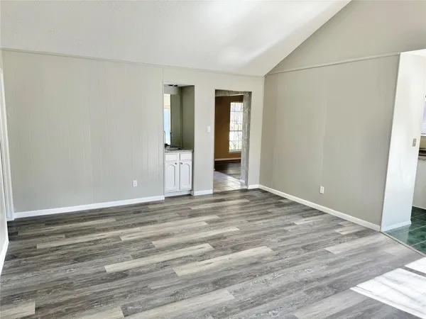 a view of an empty room with wooden floor and closet
