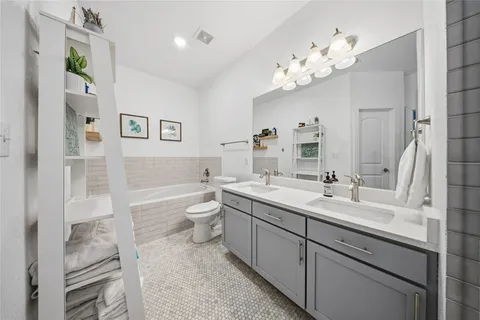 a spacious bathroom with a granite countertop sink a toilet a mirror and shower