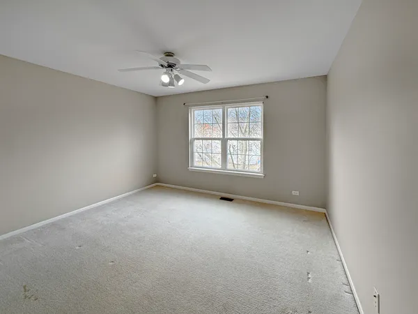 an empty room with a window and ceiling fan