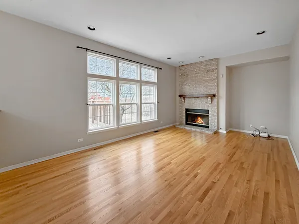 an empty room with wooden floor fireplace and windows