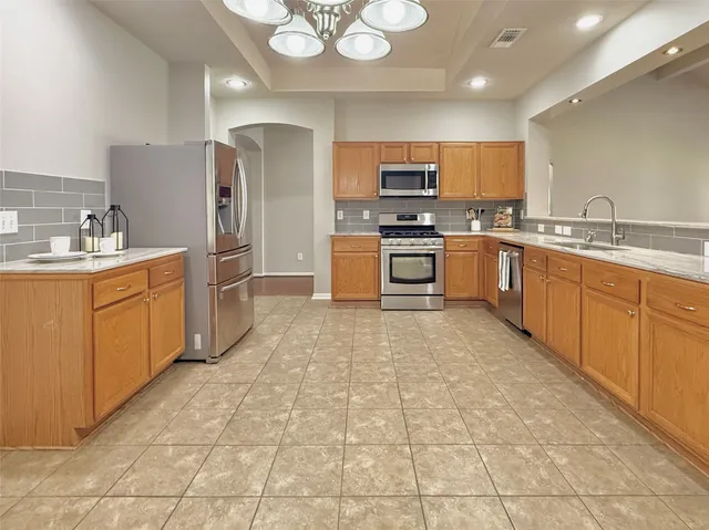 a large kitchen with stainless steel appliances lots of counter space and a sink