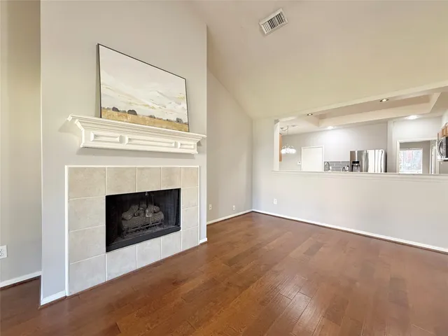 a view of a livingroom with a fireplace a ceiling fan and a kitchen view