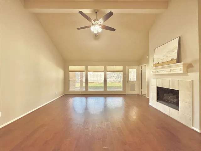 a view of an empty room with chandelier fan and fire place