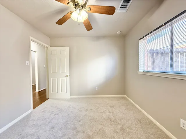 an empty room with windows and fan