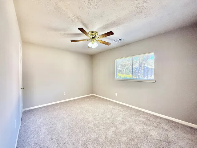 an empty room with a window and a fan