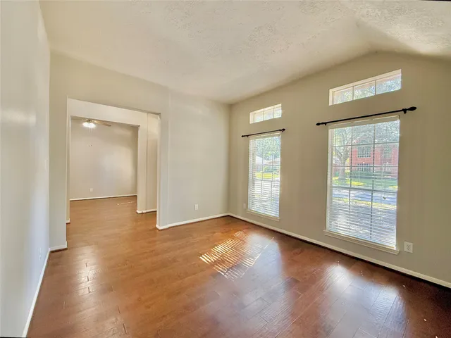 an empty room with wooden floor and windows