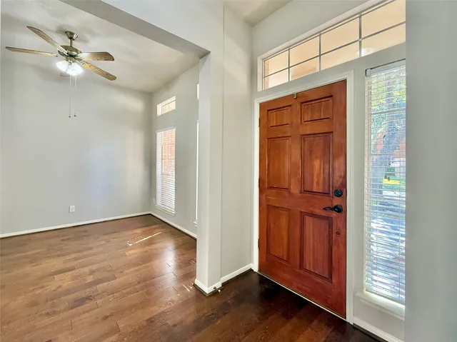 an empty room with wooden floor fan and windows