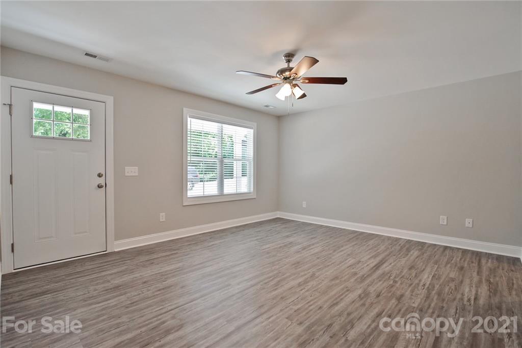 131 Powder Street Southwest Concord, NC 28025 - Photo 24 of 29 an empty room with wooden floor chandelier fan and windows