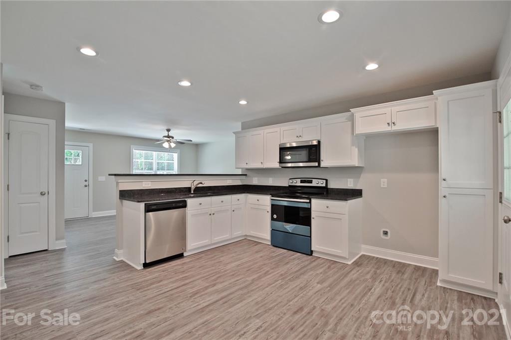 131 Powder Street Southwest Concord, NC 28025 - Photo 27 of 29 a kitchen with granite countertop a stove top oven and cabinets