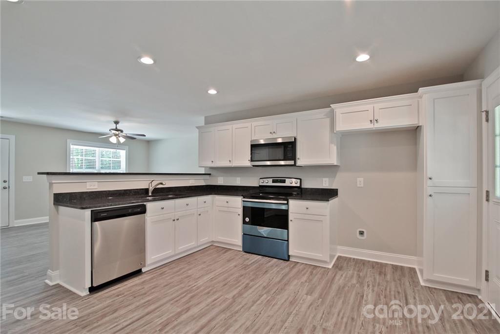 131 Powder Street Southwest Concord, NC 28025 - Photo 29 of 29 a kitchen with stainless steel appliances granite countertop a stove top oven a sink and white cabinets