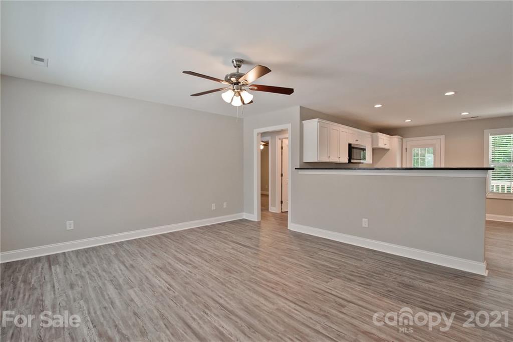 131 Powder Street Southwest Concord, NC 28025 - Photo 8 of 29 a view of a kitchen with wooden floor and a ceiling fan
