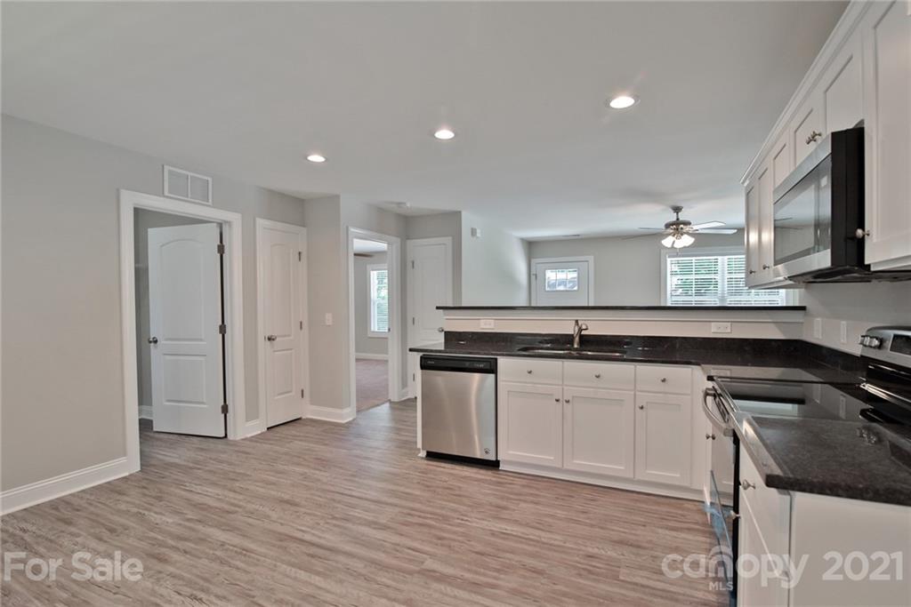 131 Powder Street Southwest Concord, NC 28025 - Photo 10 of 29 a kitchen with stainless steel appliances granite countertop a sink and a stove top oven with wooden floor